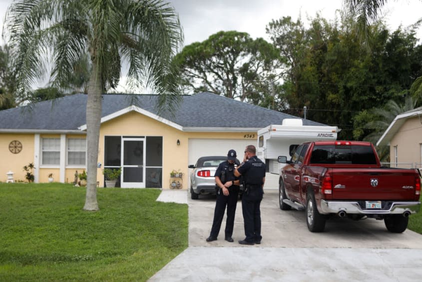 Police officers stand outside of Brian Laundrie's home.