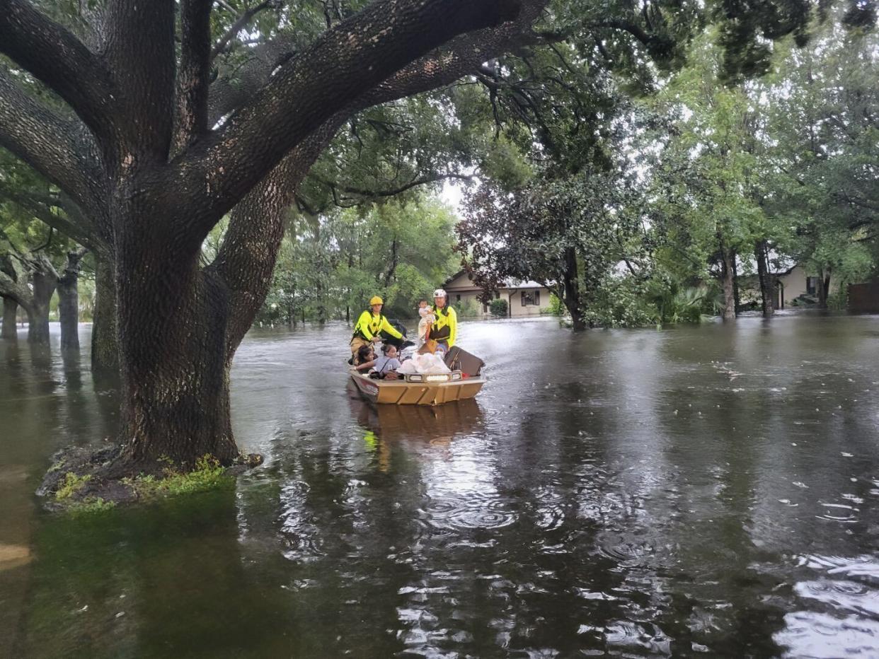 Firefighters in a small boat make their way down a flooded street, helping people stranded by Hurricane Ian.