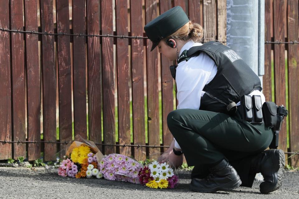 A police officer lays flowers at the scene in Londonderry (PA)