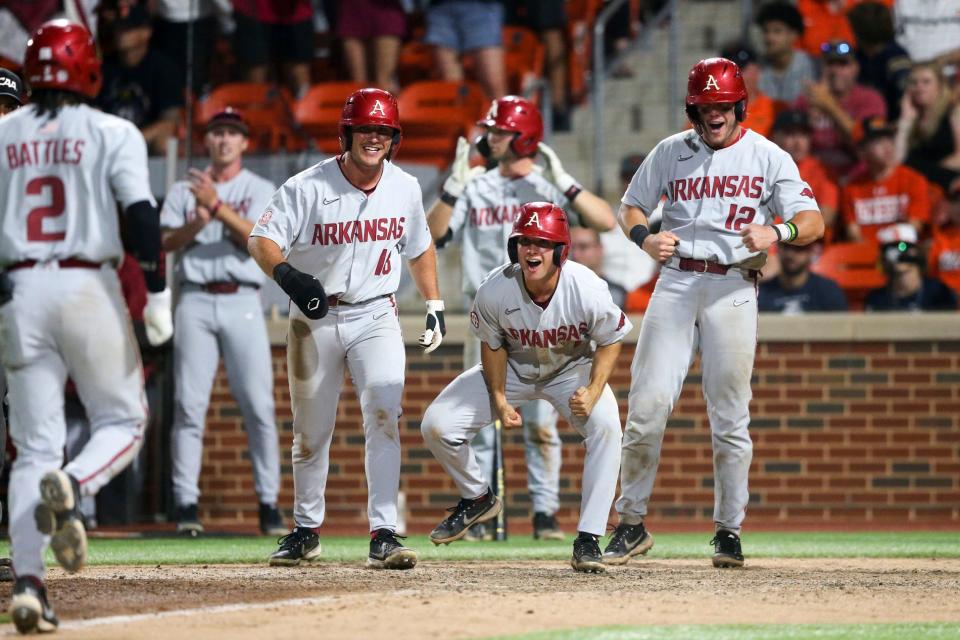 Arkansas' Chris Lanzilli (18), Robert Moore (1) and  Michael Turner (12) yell in celebration as Jalen Battles heads for home after hitting a grand slam against Oklahoma State during an NCAA college baseball tournament regional game Saturday, June 4, 2022, in Stillwater, Okla. (Ian Maule/Tulsa World via AP)