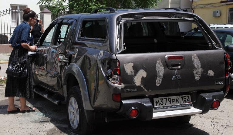 A woman looks at a damaged car at the office of the Committee Against Torture in Grozny on June 3, 2015