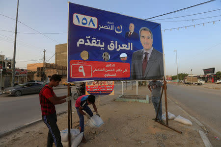 Iraqi men work on the campaign posters of candidates ahead of the parliamentary election, in Najaf, Iraq, April 20, 2018.REUTERS/Alaa Al-Marjani