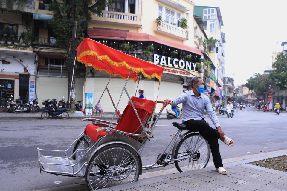 A rickshaw puller waits for customers in the old quarter of Hanoi, Vietnam on Wednesday, March 16, 2022. Vietnam on Wednesday scrapped quarantine and other travel restrictions for foreign visitors in an effort to fully reopen its border after two years of pandemic-related closure, the government said. (AP Photo/Hau Dinh)