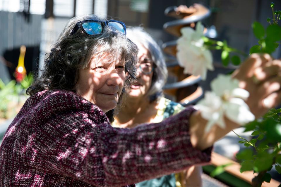 Sharron Johnson, co-chair of the Cooper-Young Garden Club, adjusts a rose while Kim Halyak, the other co-chair of the club, watches in Halyak’s backyard garden in Memphis, Tenn., on May 2, 2023. 