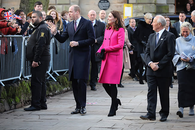 Prince William and Kate greet the crowd as they stand along the sideline of fences and security