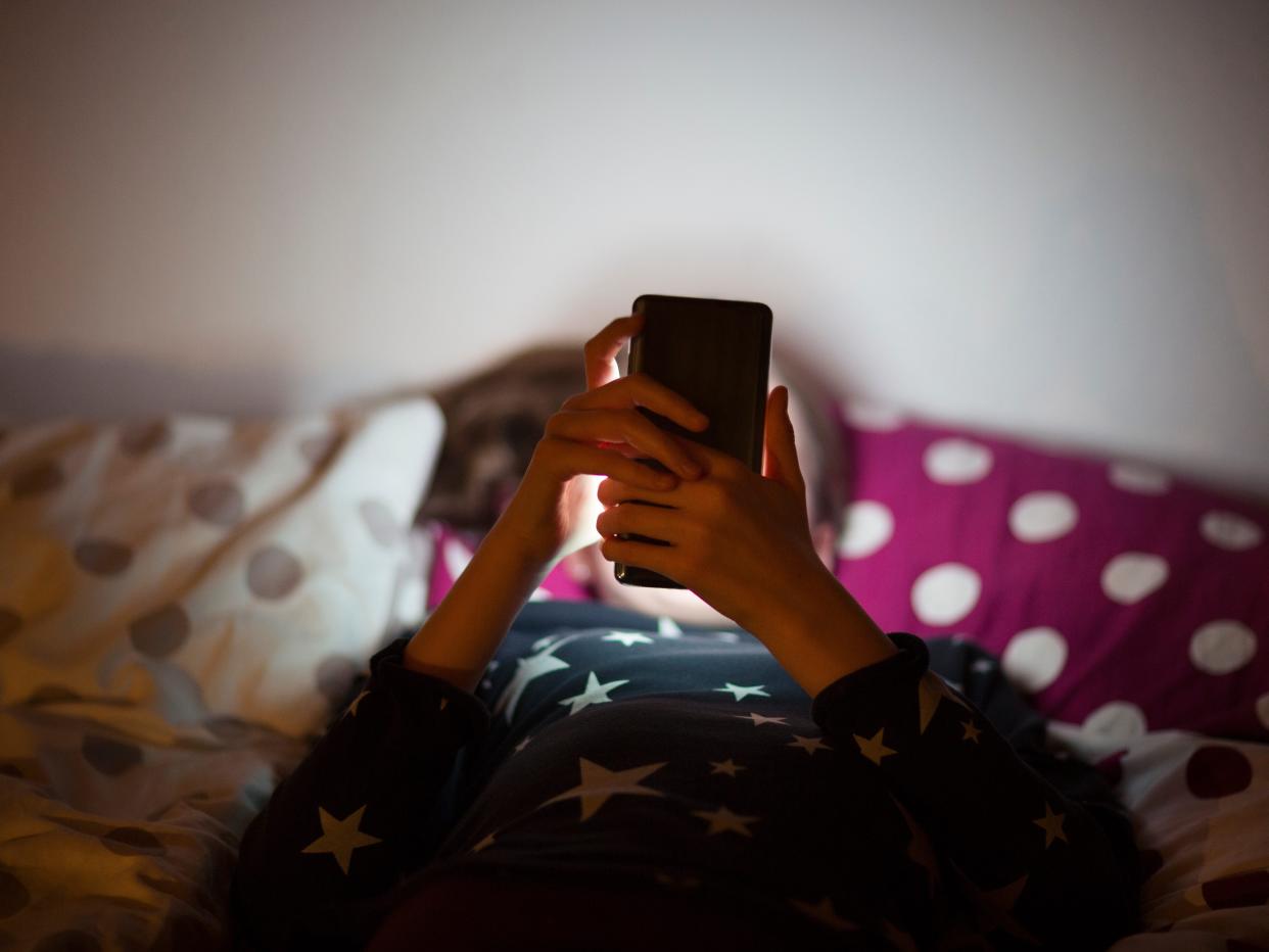 Girl lying on bed at night and using a mobile phone