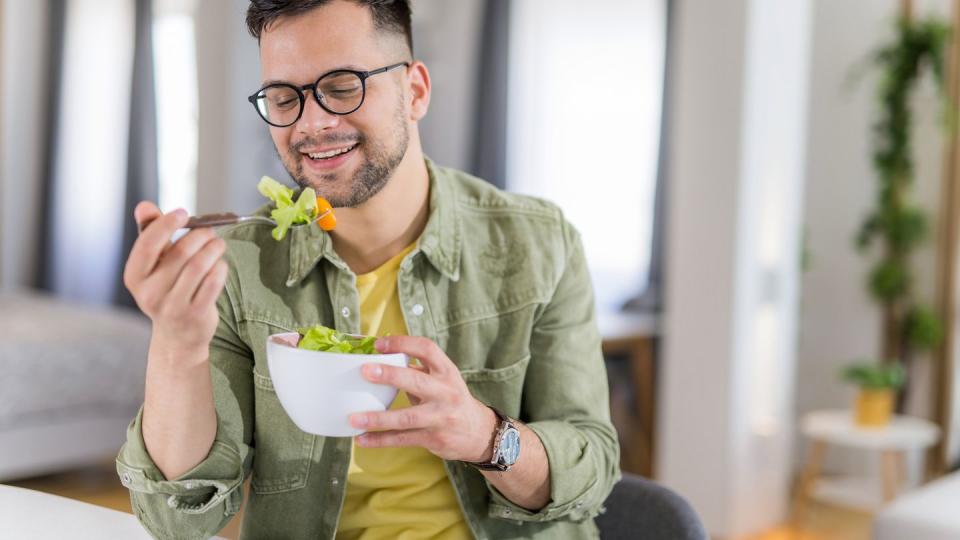 young man eating a salad at home