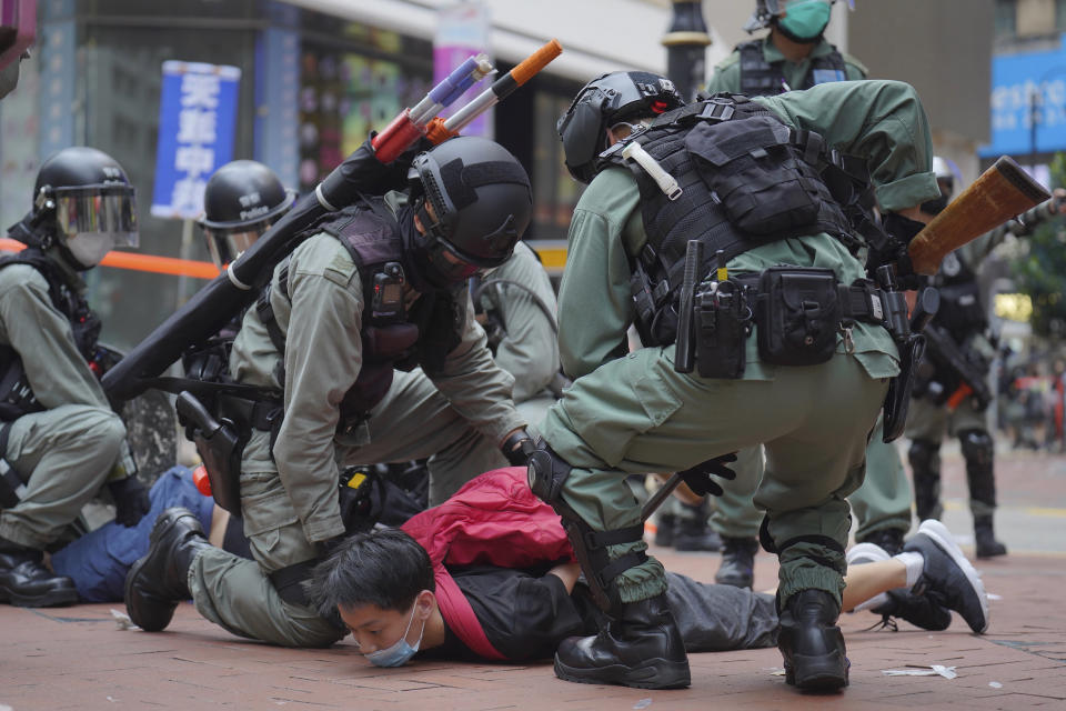 Riot police detain a protester during a demonstration against Beijing's national security legislation in Causeway Bay in Hong Kong, Sunday, May 24, 2020. Hong Kong police fired volleys of tear gas in a popular shopping district as hundreds took to the streets Sunday to march against China's proposed tough national security legislation for the city. (AP Photo/Vincent Yu)