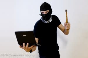 Guy with mask and hammer holding a computer