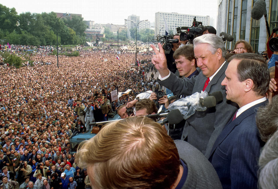 FILE - In this Thursday, Aug. 22, 1991 file photo, Russian Republic President Boris Yeltsin, second right, makes a V-sign to thousands of Muscovites, as his top associate Gennady Burbulis stands near, during a rally in front of the Russian federation building to celebrate the failed military coup in Moscow, Russia. When a group of top Communist officials ousted Soviet leader Mikhail Gorbachev 30 years ago and flooded Moscow with tanks, the world held its breath, fearing a rollback on liberal reforms and a return to the Cold War confrontation. But the August 1991 coup collapsed in just three days, precipitating the breakup of the Soviet Union that plotters said they were trying to prevent. (AP Photo/Alexander Zemlianichenko, file)