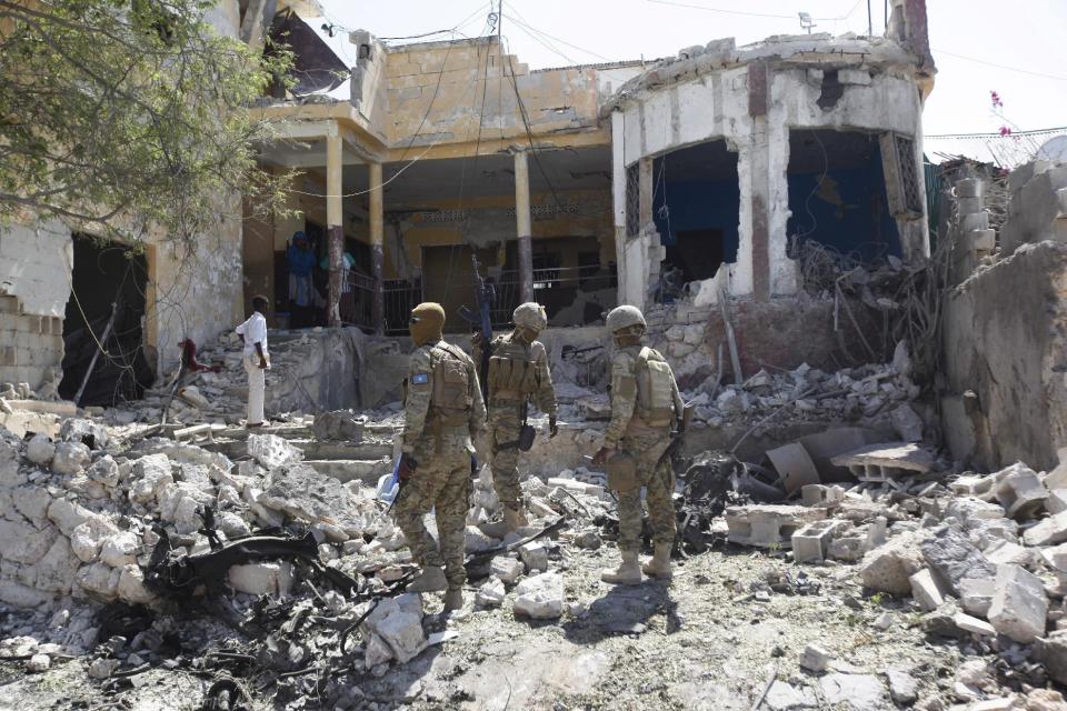 Somali soldiers stand in front of destroyed building near the scene of a suicide car bomb attack in Mogadishu, Somalia,Monday, Jan. 2, 2017. A suicide bomber detonated an explosives-laden vehicle at a security checkpoint near Mogadishu's international airport Monday, killing at least three people, a Somali police officer said. (AP Photo/Farah Abdi Warsameh)