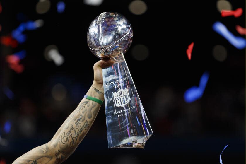 The Vince Lombardi Trophy with confetti falling as it's held up by New England Patriots strong safety Patrick Chung (23) after NFL Super Bowl 53 against the Los Angeles Rams on Sunday, Feb. 3, 2019 in Atlanta. The Patriots defeated the Rams, 13-3. (Ryan Kang via AP)