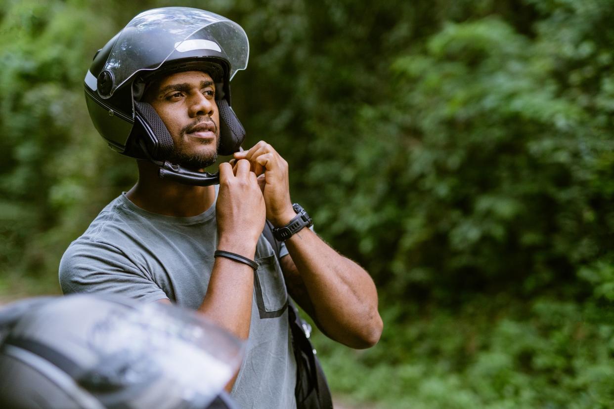 Biker putting on helmet in nature park