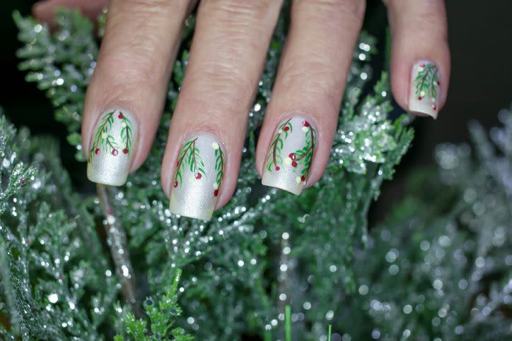 holiday inspired nail art with silver polish and mistletoe and berries painted on top