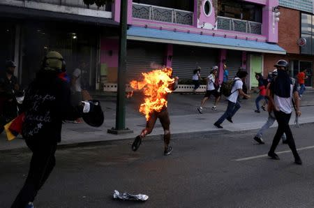A man who was set on fire by people accusing him of stealing during a rally against Venezuela's President Nicolas Maduro runs amidst opposition supporters in Caracas, Venezuela, May 20, 2017. REUTERS/Marco Bello