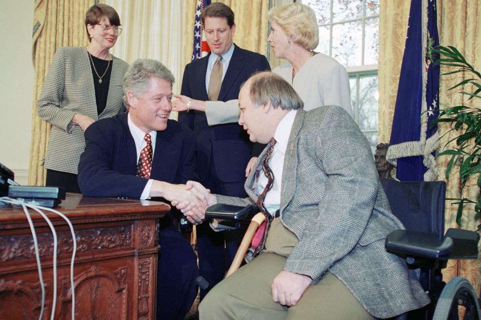 U.S. President Bill Clinton shakes hands with James Brady in the Oval Office of the White House in Washington, Wednesday, Nov. 24, 1993 after the Senate leadership called the President via telephone, to him that the Brady gun bill had passed. Looking on from left are, Attorney General Janet Reno, Vice President Al Gore and BradyÕs wife Sarah.