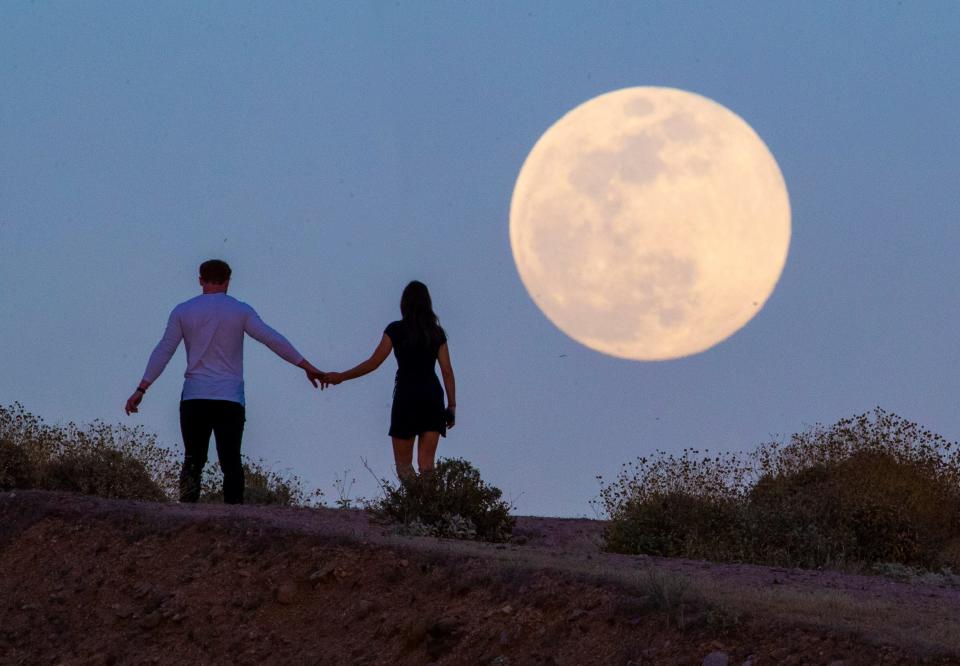 Clint and Kaylee Frazier enjoy the sunset as a super flower moon rises over Fountain Hill, Ariz. on May 6, 2020. This "Flower Moon" was the last in a series of four supermoons in quick succession in 2018 and gets it's name for the large number of flowers that bloom in May.