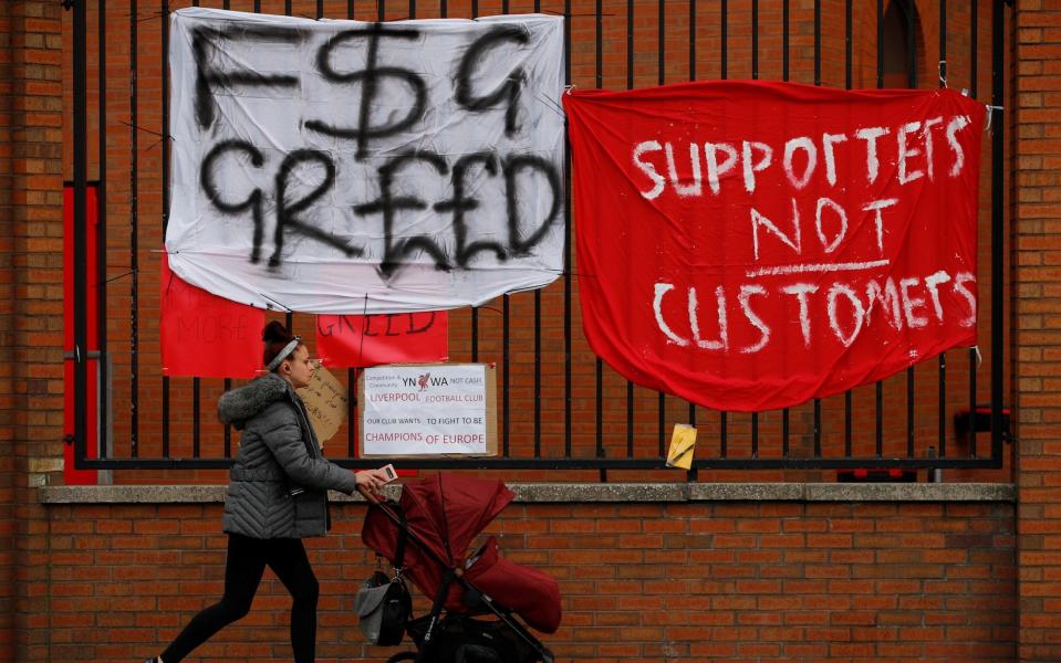 A woman walks past protest banners hung outside Anfield - PHIL NOBLE /Reuters