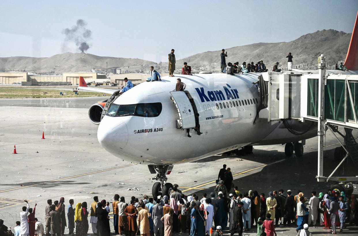 Afghan people climb atop a plane as they wait at Hamid Karzai International Airport in Kabul on Aug. 16, 2021. (Wakil Kohsar / AFP - Getty Images)