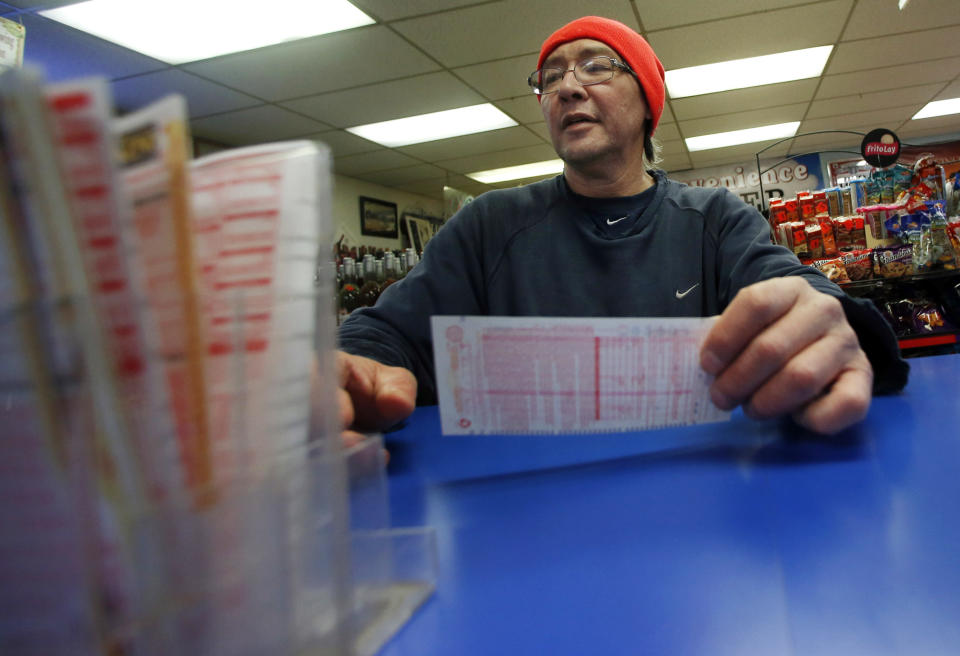 Robert Allen selects a Powerball lottery ticket to fill out at a convenience store in North Andover, Mass., Wednesday, Feb. 19, 2014. The estimated Powerball jackpot is $400 million. (AP Photo/Elise Amendola)