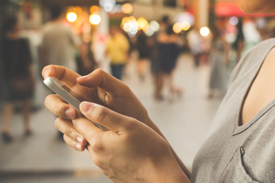 A woman using a mobile phone on a busy street.