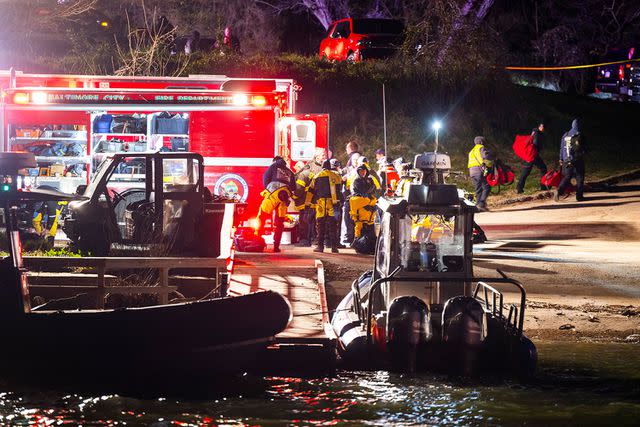 <p>JIM LO SCALZO/EPA-EFE/Shutterstock</p> Rescue personnel gather on the shore of the Patapsco River