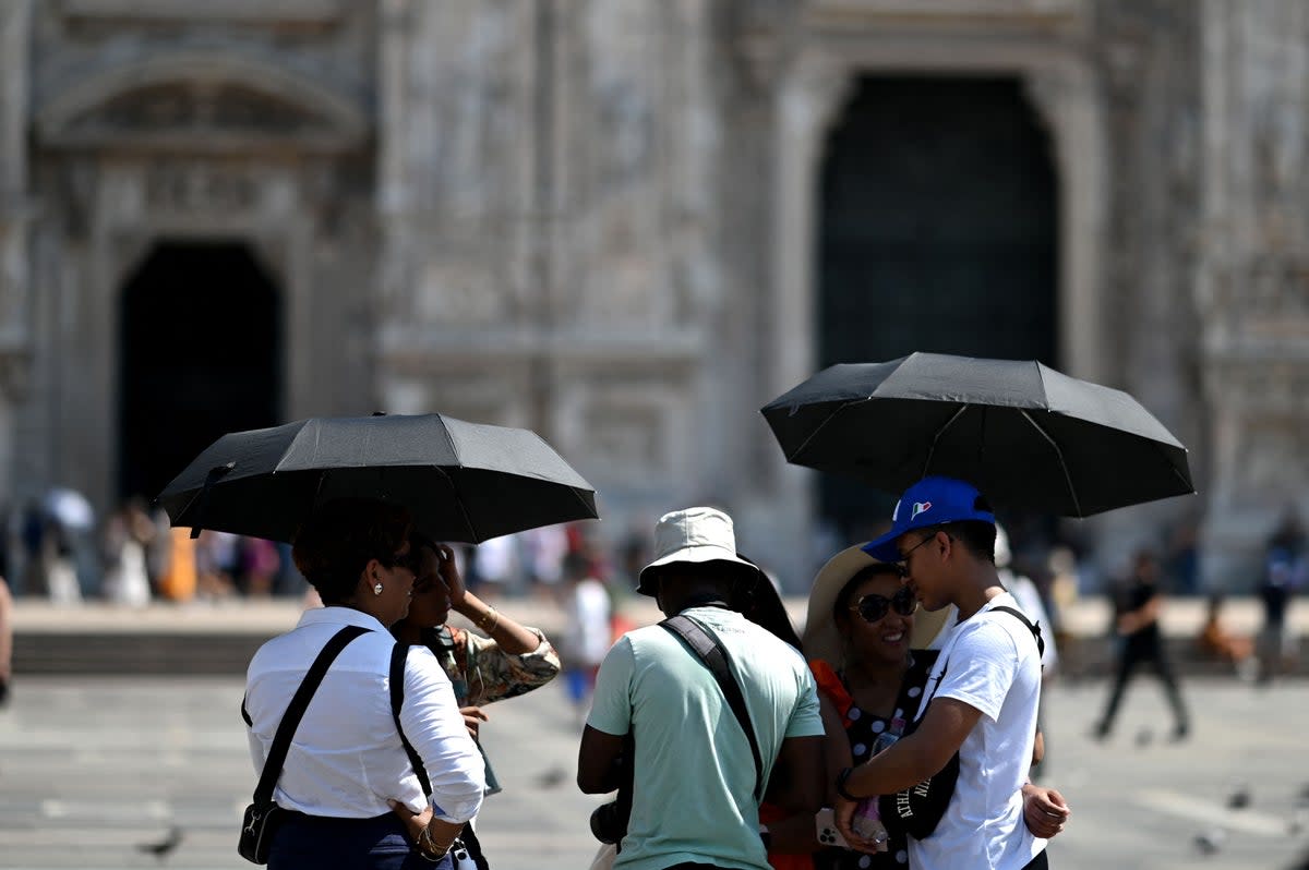 Tourists protect themselves from the heat with umbrellas in front of the Duomo Cathedral in the touristic centre of Milan (AFP via Getty Images)