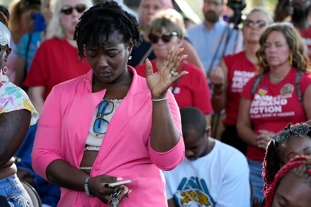 A woman attending a vigil for the victims of Saturday's mass shooting bows her head in prayer Sunday, Aug. 27, 2023, in Jacksonville, Fla.