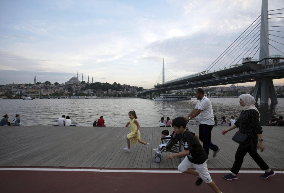 People walk near Golden Horn in Istanbul, Friday, June 21, 2019, ahead of June 23 re-run of Istanbul elections. Millions of voters in Istanbul go back to the polls for a controversial mayoral election re-run Sunday, as President Recep Tayyip Erdogan's party tries to wrestle back control of Turkey's largest city. Suleymaniye Mosque is in the background. (AP Photo/Burhan Ozbilici)