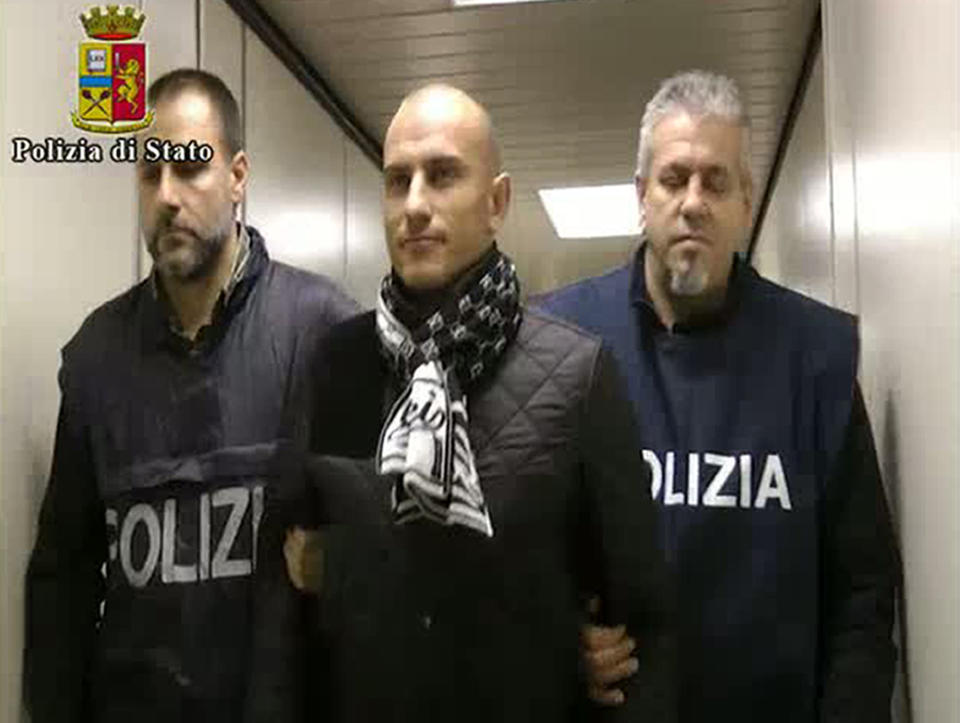 In this frame grab from a video released by the Italian Police, Serbian footballer Almir Gegic, who has been wanted since June 2011 for alleged involvement in a widespread match-fixing case, is escorted by police after he arrived at the Malpensa airport in the outskirts of Milan, Italy, Monday evening, Nov. 26, 2012. After more than a year on the run, Gegic turned himself in and was brought to a jail in Cremona, where prosecutor Roberto Di Martino's match-fixing inquiry is based. More than 50 people have been arrested so far and more than 100 are under investigation. (AP Photo/Italian Police, HO)