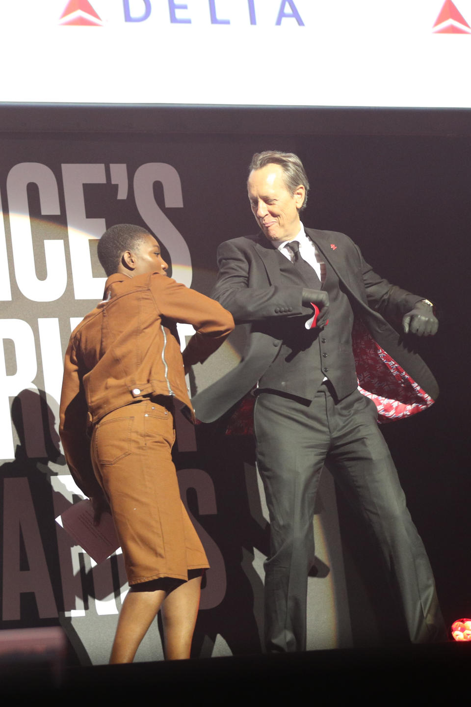 Michaela Coel and Richard E Grant greet each other with an elbow bump on stage at the annual Prince's Trust Awards 2020 held at the London Palladium.