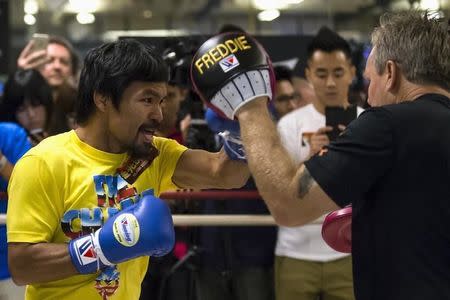 Boxer Manny Pacquiao of the Philippines practices with trainer Freddie Roach (R) during a media workout in Hong Kong in this file photo taken on October 27, 2014. REUTERS/Tyrone Siu