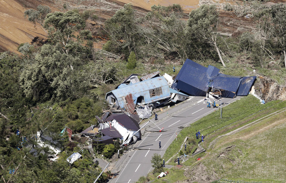 Police search missing persons around houses destroyed by a landslide after an earthquake in Atsuma town, Hokkaido, northern Japan, Thursday, Sept. 6, 2018. A powerful earthquake rocked Japan’s northernmost main island of Hokkaido early Thursday, triggering landslides that crushed homes, knocking out power across the island, and forcing a nuclear power plant to switch to a backup generator. (Kyodo News via AP)