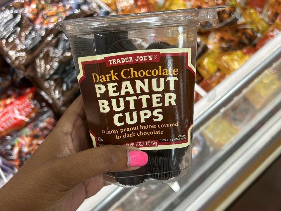 Woman holding a container of Trader Joe's dark-chocolate peanut butter cups.