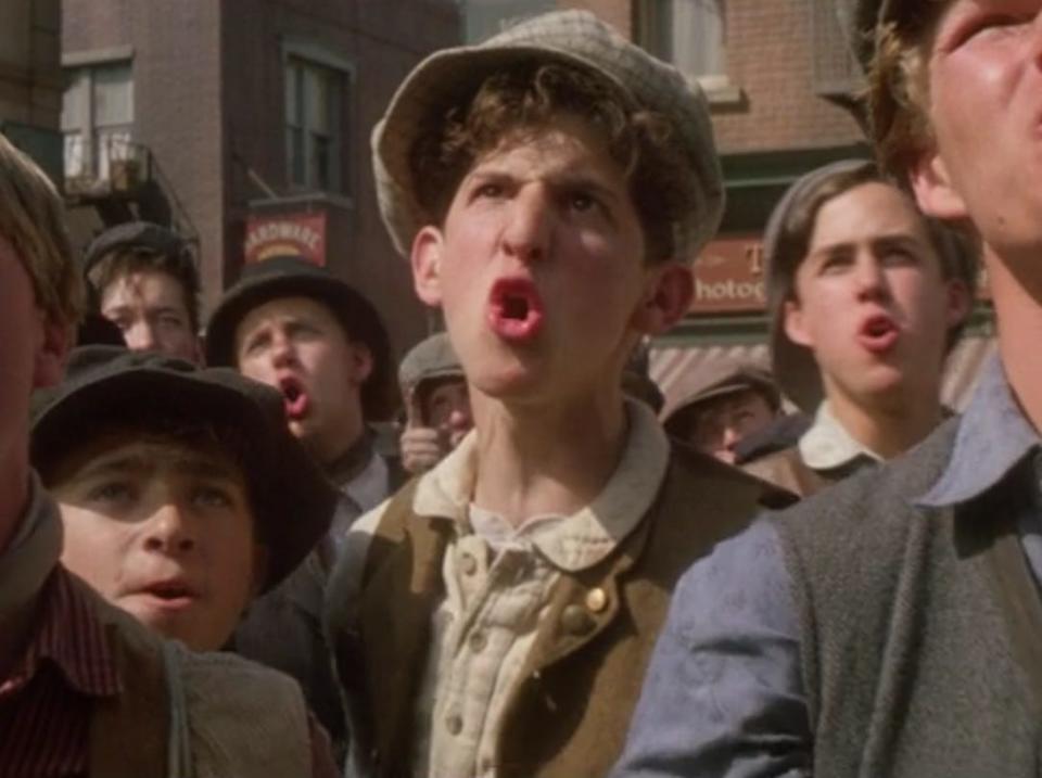 Crutchy (Marty Belfasky) and newsboys singing in Newsies