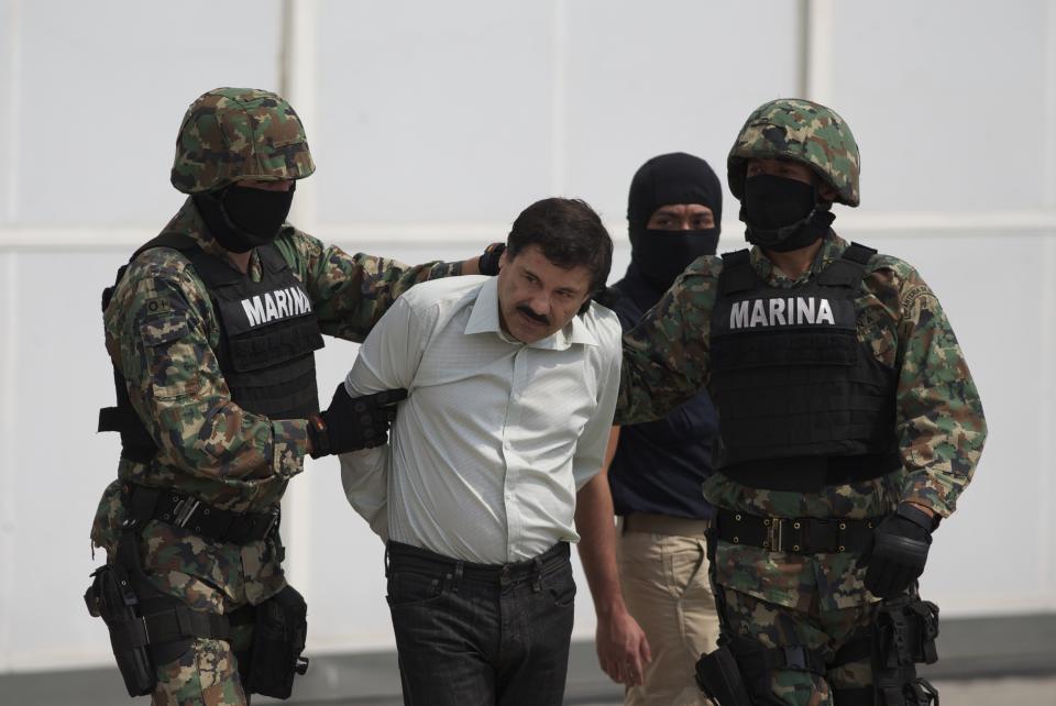 Joaquín "El Chapo" Guzmán es escoltado por infantes de la Marina de México en un hangar de la Armada, en Ciudad de México, el sábado 22 de febrero de 2014. El líder del Cártel de Sinaloa fue capturado el viernes. (Foto AP/Eduardo Verdugo)