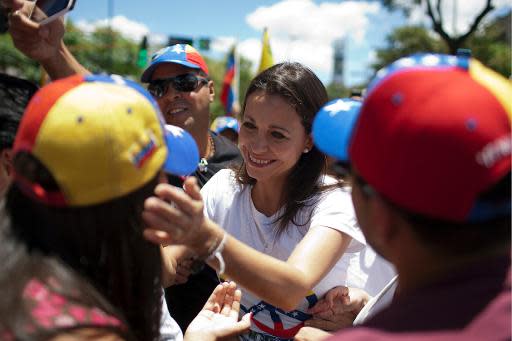 La diputada opositora l venezolana María Corina Machado (C), destituida por el oficialismo, saluda a simpatizantes durante una marcha contra el gobierno de Nicolás Maduro, en Caracas, el 29 de marzo de 2014. (AFP | Federico Parra)