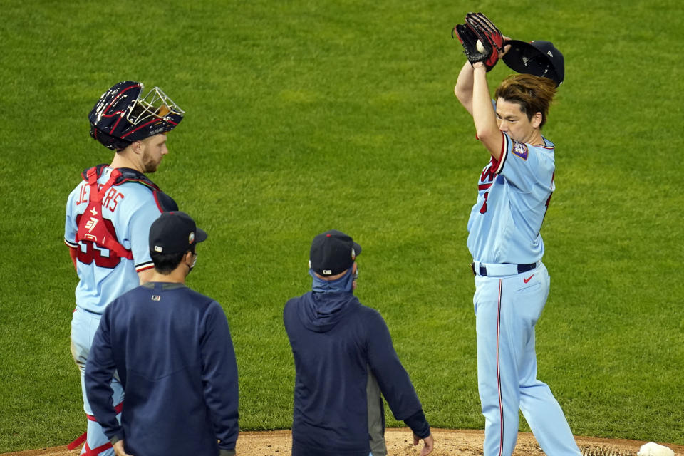 Minnesota Twins pitcher Kenta Maeda, right, wipes his face as he gets a mound visit from catcher Ryan Jeffers, left, a translator and pitching coach Wes Johnson, second from right, during the sixth inning of the team's baseball game against the Detroit Tigers, Wednesday, Sept. 23, 2020, in Minneapolis. (AP Photo/Jim Mone)