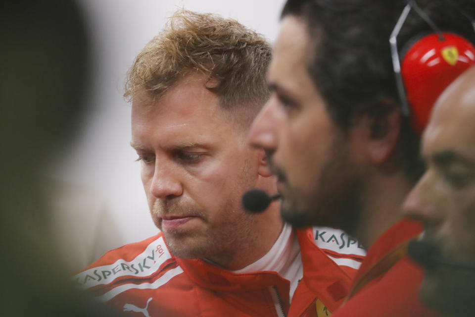 Ferrari driver Sebastian Vettel of Germany, left, talks with team mechanics during second practice at the Marina Bay City Circuit ahead of the Singapore Formula One Grand Prix in Singapore, Friday, Sept. 14, 2018. (AP Photo/Vincent Thian)