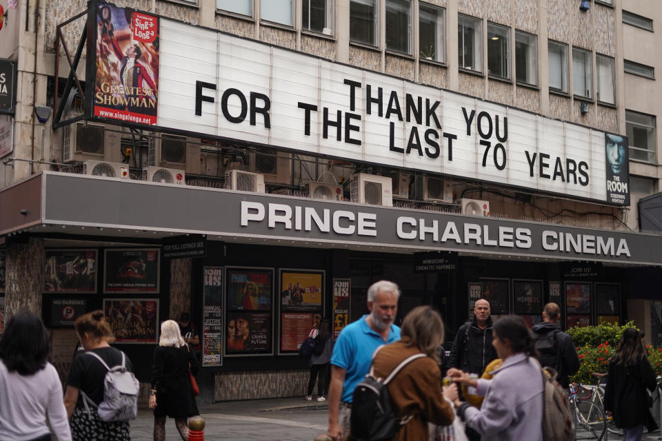 People walks past Prince Charles Cinema, which displays a message reading 'Thank you for the last 70 years', in Soho, in London, Tuesday, Sept. 13, 2022. Queen Elizabeth II, Britain's longest reigning monarch, will lie in state at Westminster Palace from Wednesday.(AP Photo/Alberto Pezzali)