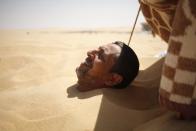 A patient is buried in the hot sand in Siwa, Egypt, August 12, 2015. (REUTERS/Asmaa Waguih)