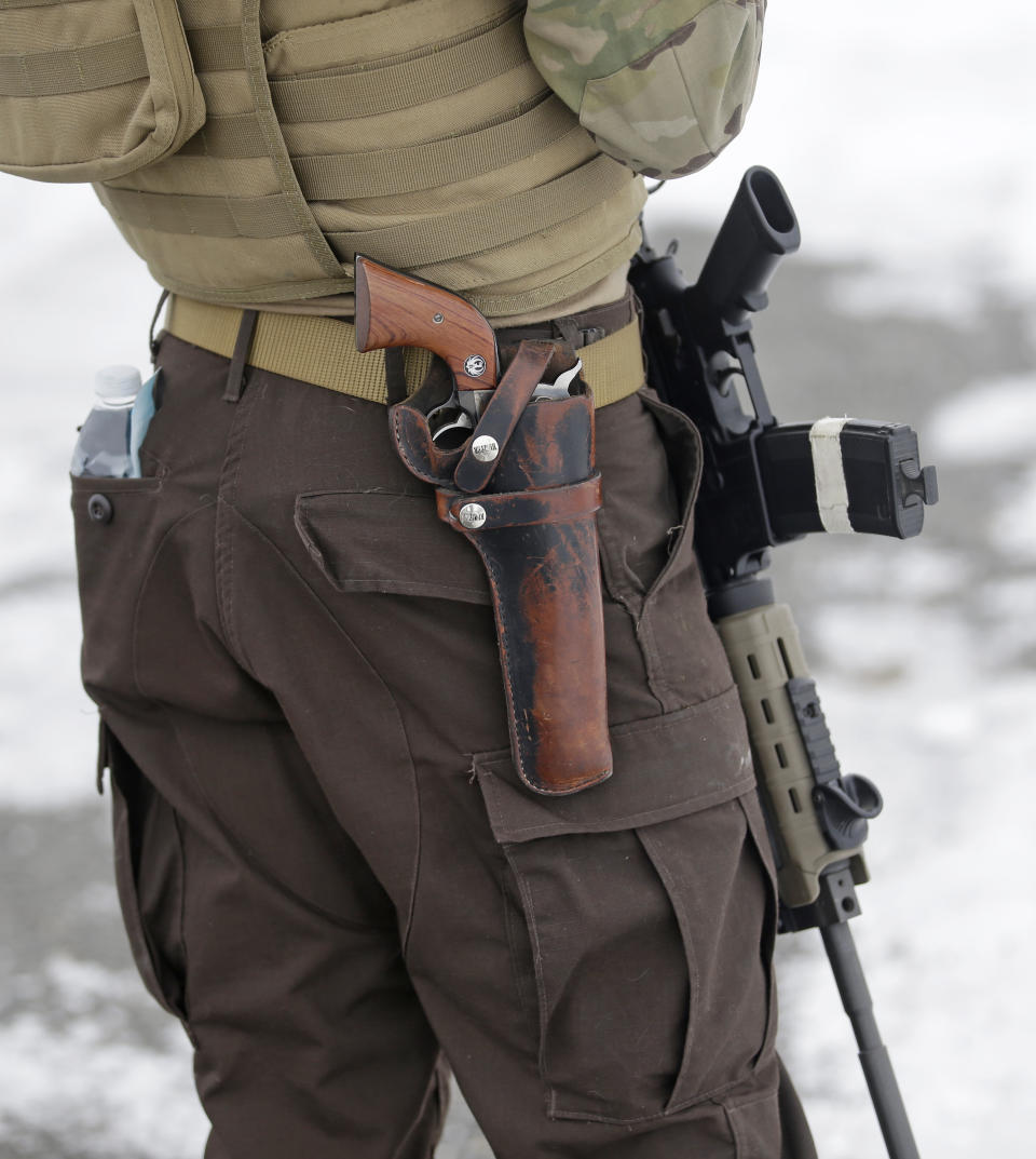 FILE - In this Jan. 9, 2016, file photo, a man stands guard after several organizations arrived at the Malheur National Wildlife Refuge near Burns, Ore. A new report from the Government Accountability Office highlights violence against public lands employees amid heightened tensions with anti-government groups. (AP Photo/Rick Bowmer, File)