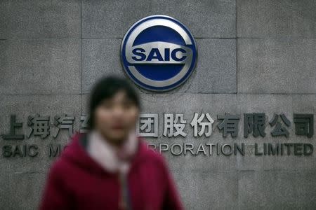 A woman walks past the gate of SAIC Motor Corporation Limited in Shanghai January 26, 2013. REUTERS/Aly Song