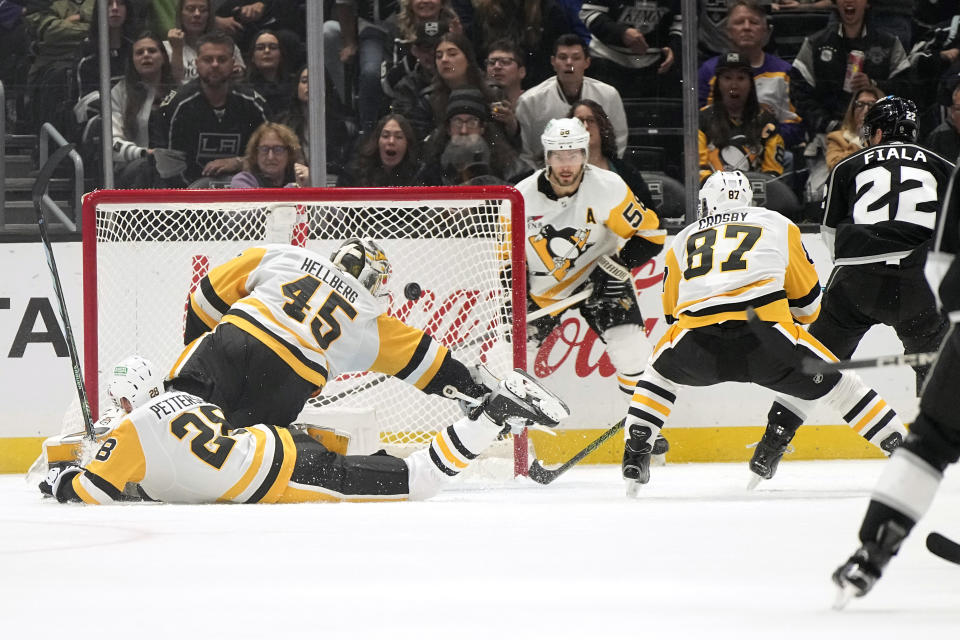 Los Angeles Kings left wing Kevin Fiala (22) scores on Pittsburgh Penguins goaltender Magnus Hellberg (45) as defenseman Marcus Pettersson (28), center Sidney Crosby (87) and defenseman Kris Letang (58) defend during the third period of an NHL hockey game Thursday, Nov. 9, 2023, in Los Angeles. (AP Photo/Mark J. Terrill)