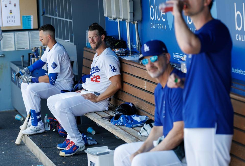 El abridor de los Dodgers Clayton Kershaw, segundo desde la izquierda, se sienta en el dugout local con otros miembros del equipo.