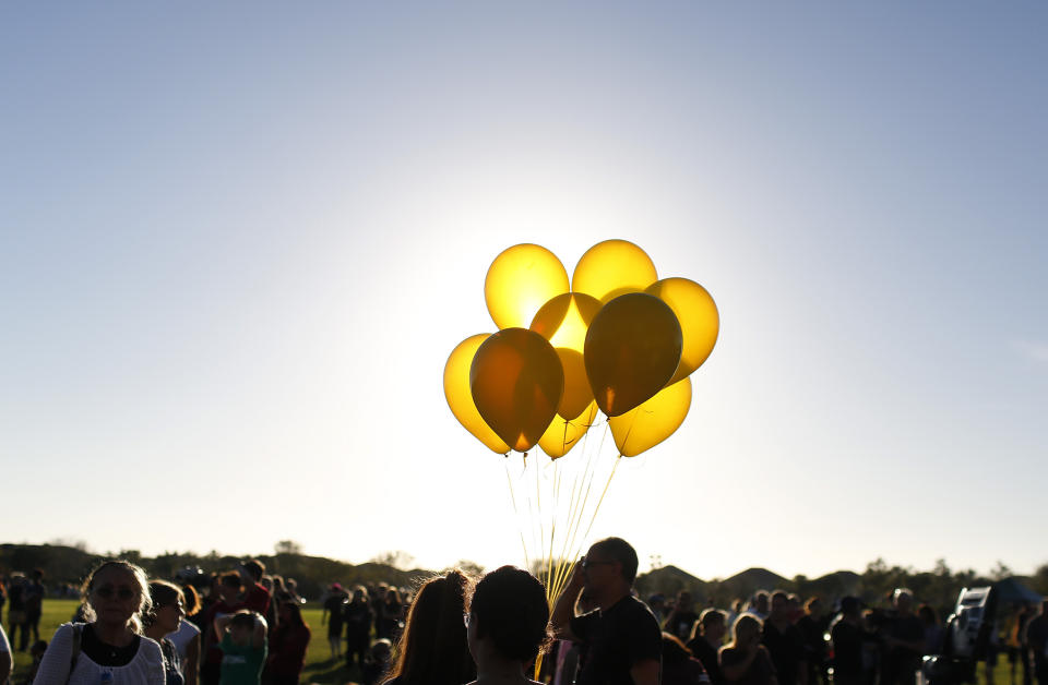 FILE - Yellow balloons are held by students during a vigil at Pine Trails Park for the victims of the shooting at Marjory Stoneman Douglas High School, in Parkland, Fla., on Thursday, Feb. 15, 2018. (AP Photo/Brynn Anderson, File)
