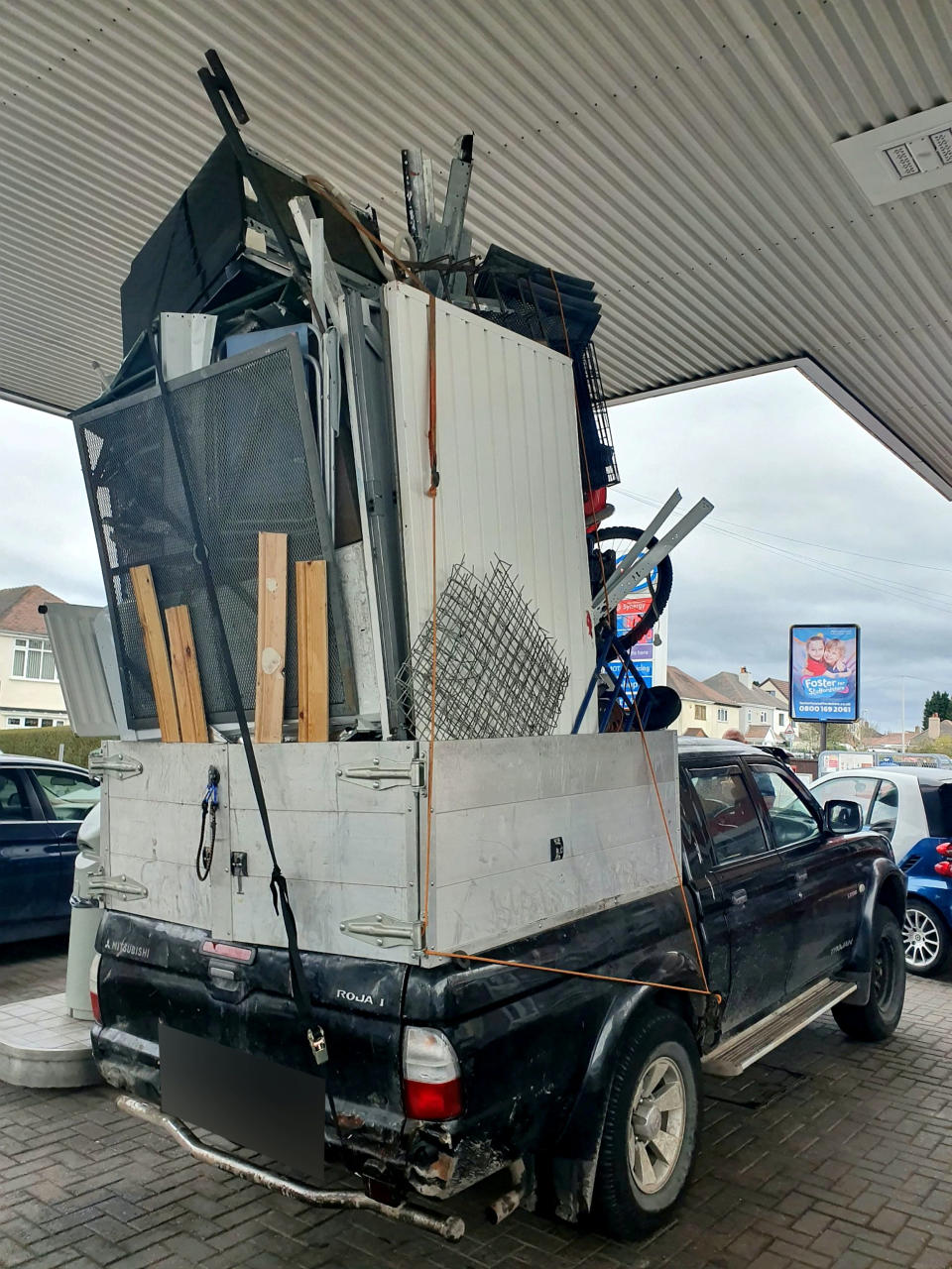 Police were left stunned after pulling over this dangerously overloaded pick-up truck which was piled high with a mountain of rubbish held together by pieces of rope. (SWNS)