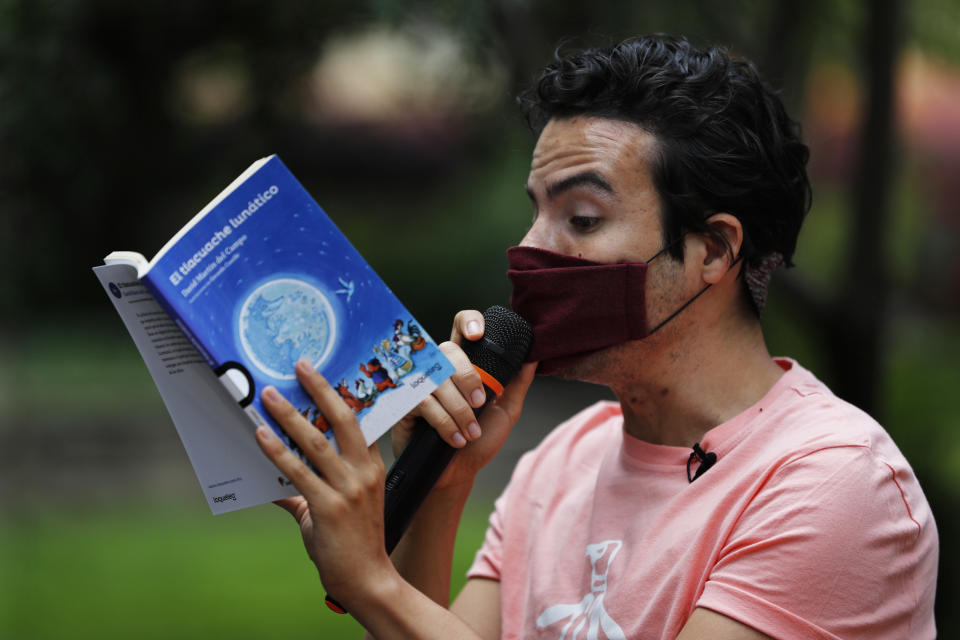 Percibald Garcia uses a microphone to read aloud children's books amid the high-rise housing complex of Tlatelolco, in Mexico City, Saturday, July 18, 2020. Confinement during the coronavirus pandemic has been especially tedious for children, so the young architect sets out every afternoon with a microphone and a loudspeaker to walk the neighborhood where he lives and provide entertainment. (AP Photo/Marco Ugarte)