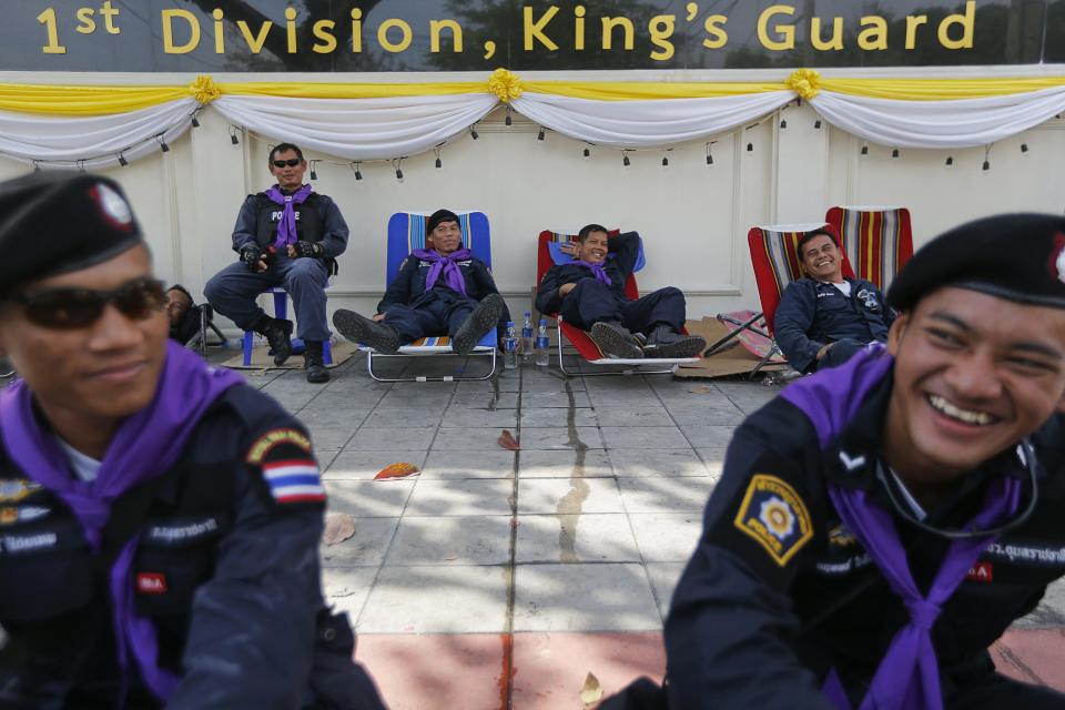 Policemen share a light moment as anti-government protesters enter the compound of the metropolitan police headquarters, the site of fierce clashes over the last few days in Bangkok December 3, 2013. Thailand's government ordered police to stand down and allow protesters into state buildings on Tuesday, removing a flashpoint for clashes and effectively bringing an end to days of violence in Bangkok in which five people have died. REUTERS/Damir Sagolj (THAILAND - Tags: POLITICS CIVIL UNREST)