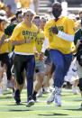 NFL football and former Baylor quarterback Robert Griffin III, right, runs onto the field with fans before Baylor played BYU in an NCAA college football game, Saturday, Oct. 16, 2021, in Waco, Texas. (AP Photo/Ron Jenkins)